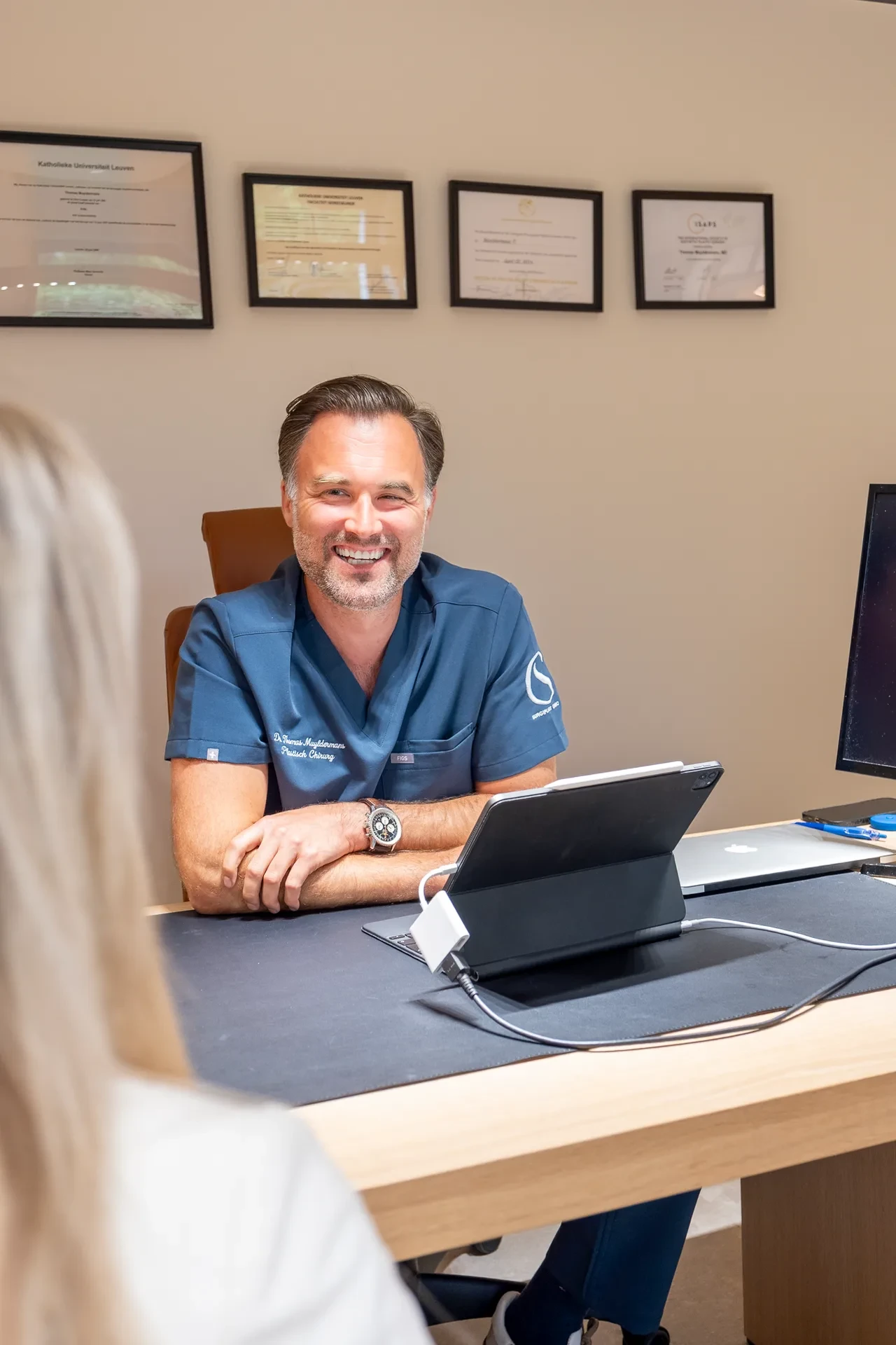 Dr. Muyldermans glimlacht breed tijdens een consultatiegesprek.