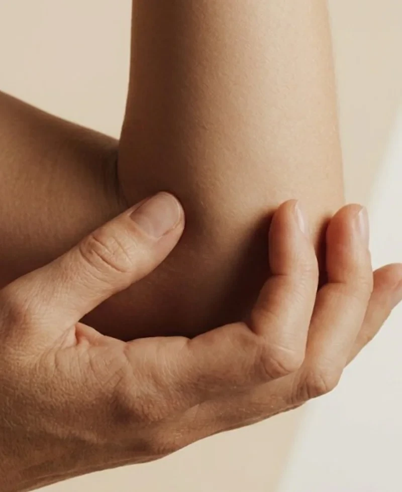 Hand die de elleboog vasthoudt bij nervus ulnaris problematiek.