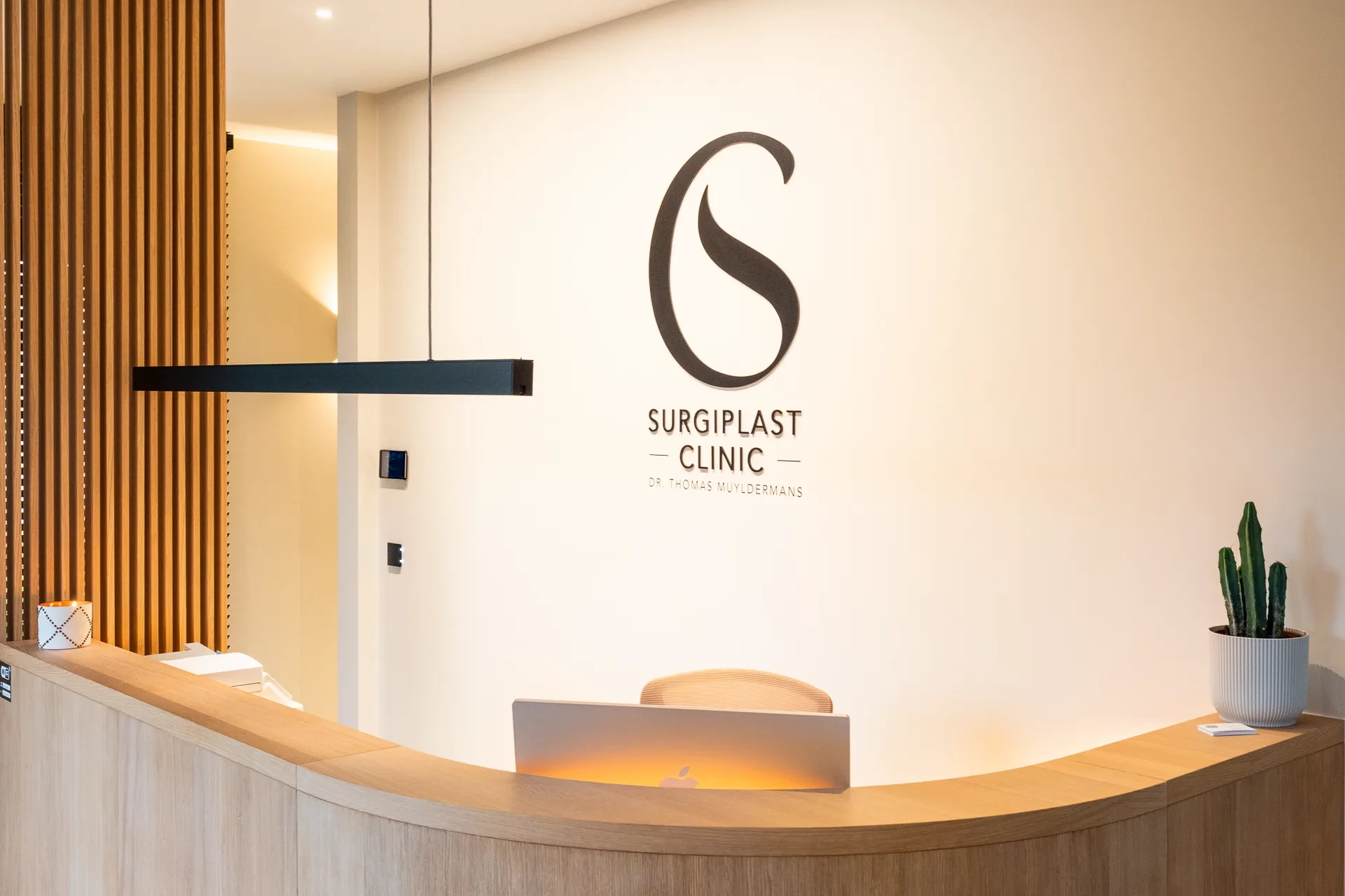 De houten receptiebalie met het Surgiplast Clinic-logo op de muur.